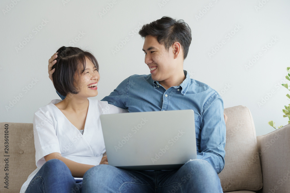 Asian young couple make fun of working on laptop. they sit on sofa in the contemporary living room. Asian young couple make fun of working on laptop. they sit on sofa in the contemporary living room.