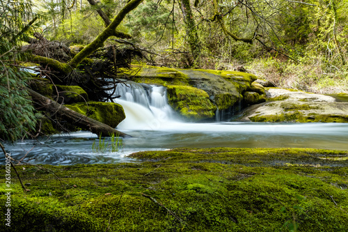 beautiful waterfall besides green moss covered rocks inside forest