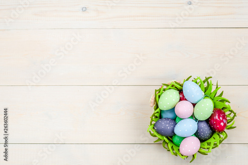 Easter eggs in basket on wooden background. Backdrop with empty space for text