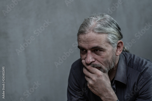 Sad old man on dark background. Empty space for text