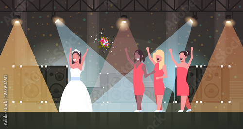 bride in white dress throwing bouquet for mix race bridesmaids to catch girls having fun on stage lights effects disco studio wedding day concept full length horizontal