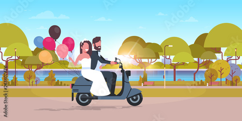 just married couple riding motor scooter with colorful balloons bride and groom having fun wedding day concept city urban park landscape background full length horizontal flat