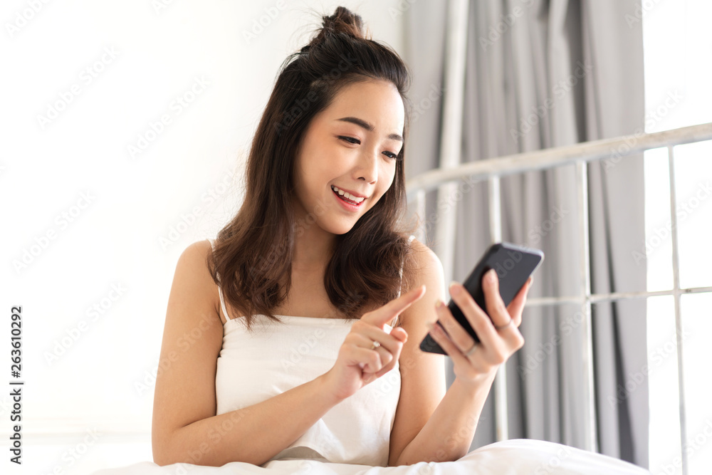 Happy woman relaxing using and talking by smartphone on the bed at home.technology and communication concept Happy woman relaxing using and talking by smartphone on the bed at home.technology and communication concept