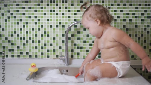 Cute toddler girl brushing her teeth in the bathroom. Cute baby sitting in the sink. 