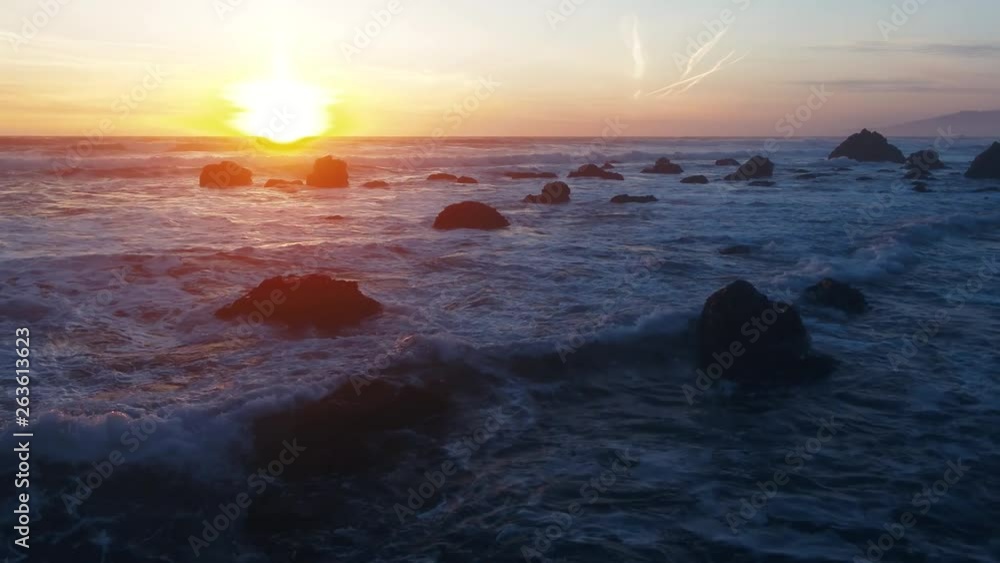 Drone captures a setting sun at golden hour over empty a rocky beach and surf break. Haze and setting sun create a dreamy and surreal vibe. Drone captures a setting sun at golden hour over empty a rocky beach and surf break. Haze and setting sun create a dreamy and surreal vibe.