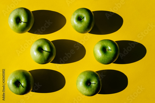 Summer pattern of fresh green apples on yellow background