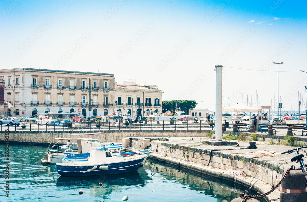 View of old street, facades of ancient buildings and sail boats in seafront of Ortygia (Ortigia) Island, Syracuse, Sicily, Italy.