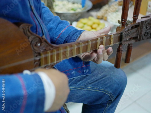 Hands of a musician playing Seung, plucked lute from the Lanna region of northern Thailand, made of hardwood - Traditional Thai musical instrument photo