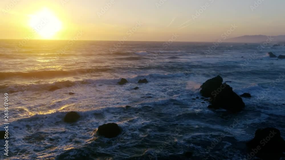 Drone captures a setting sun at golden hour over empty a rocky beach and surf break. Haze and setting sun create a dreamy and surreal vibe. Drone captures a setting sun at golden hour over empty a rocky beach and surf break. Haze and setting sun create a dreamy and surreal vibe.