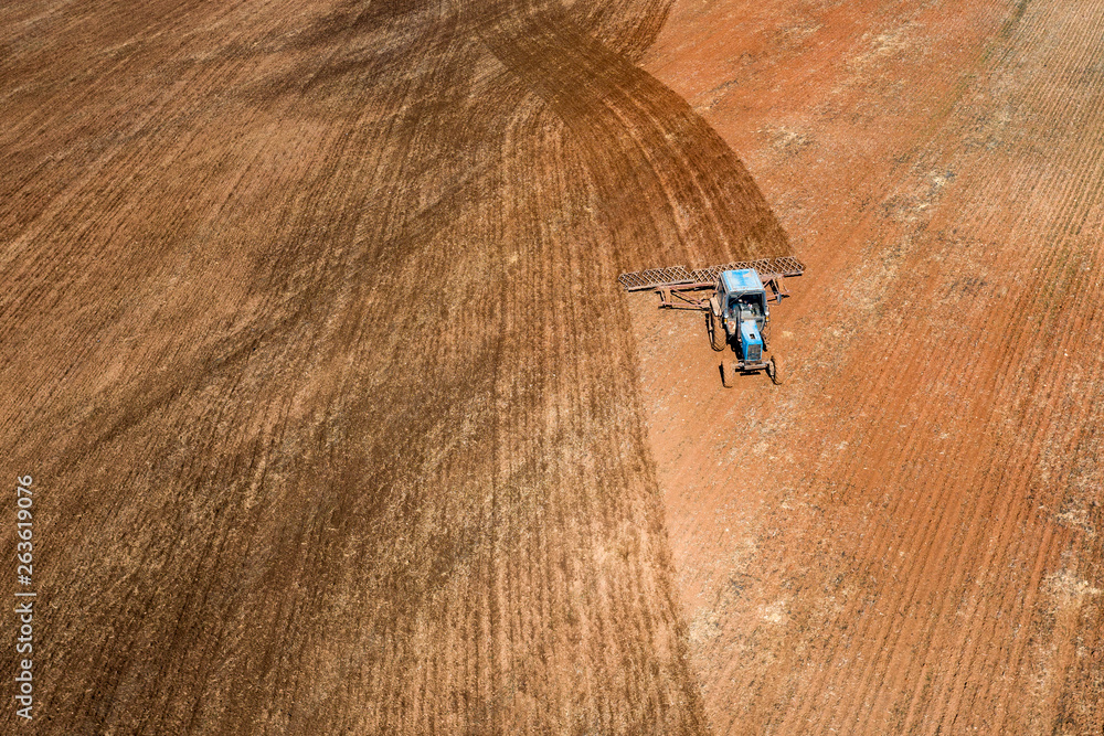 Spring agricultural work in the fields. Plowing and harrowing the soil with a tractor. The view from the top. Copy space. Concept: Timely preparation of soil for sowing is the key to a good harvest. Spring agricultural work in the fields. Plowing and harrowing the soil with a tractor. The view from the top. Copy space. Concept: Timely preparation of soil for sowing is the key to a good harvest.