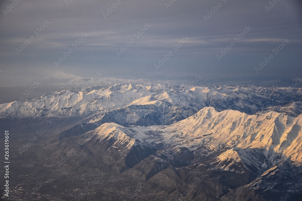 Aerial view from airplane of the Wasatch Front Rocky Mountain Range with snow capped peaks in winter including urban cities of Provo, Farmington Bountiful, Orem and Salt Lake City. Utah. United States