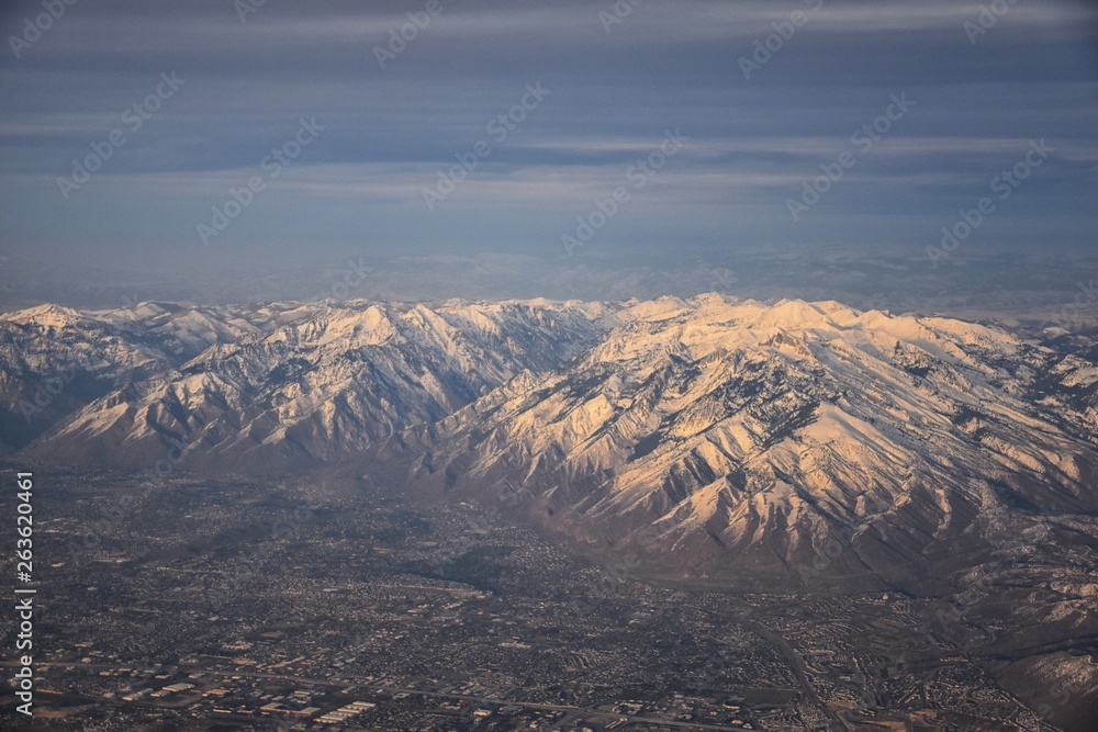 Aerial view from airplane of the Wasatch Front Rocky Mountain Range with snow capped peaks in winter including urban cities of Provo, Farmington Bountiful, Orem and Salt Lake City. Utah. United States