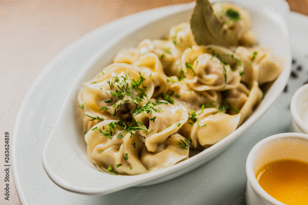 Meat dumplings or pelmeni served with sour cream and dill Meat dumplings or pelmeni served with sour cream and dill