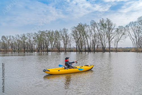Kayak fishing at lake. Fisherwoman on inflatable boat with fishing tackle.