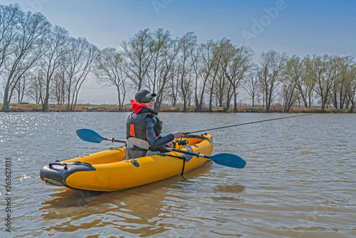 Kayak fishing at lake. Fisherwoman on inflatable boat with fishing tackle.