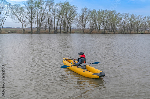 Kayak fishing at lake. Fisherwoman on inflatable boat with fishing tackle.