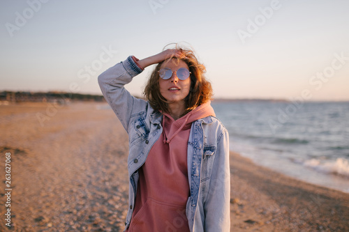 Young beautiful happy woman having good time at the beach on sunset time