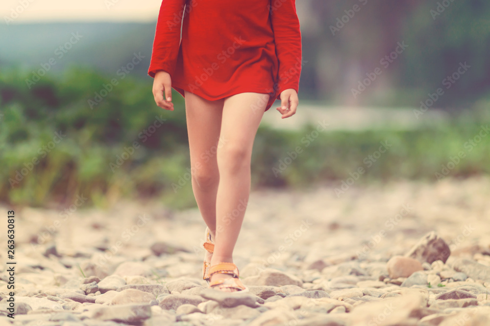 Girl in the red dress walking on the stones