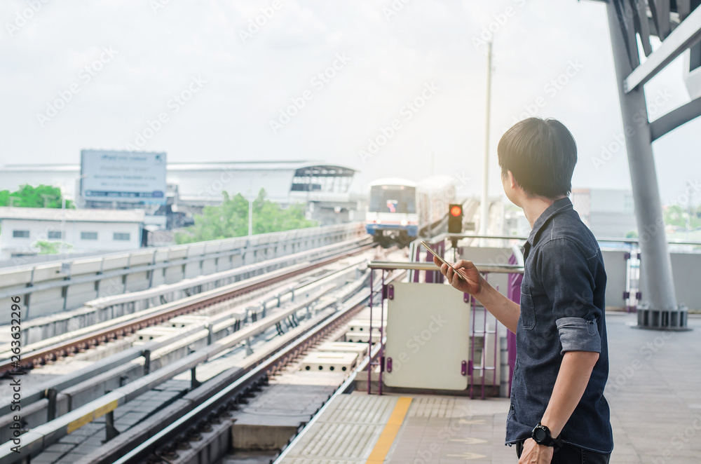BANGKOK THAILAND, April 7,2019 : Asian man passenger using smartphone and looking BTS in train station ,skytrain wait on BTS Skytrain station.