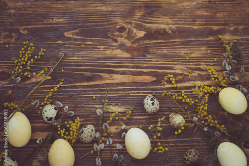 Easter background with easter eggs and spring flowers. Yellow eggs on wooden background. Place for inscription. top view photo