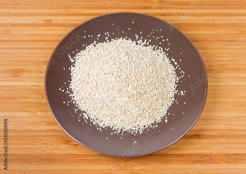 Uncooked fine-ground barley groat on the brown dish photo