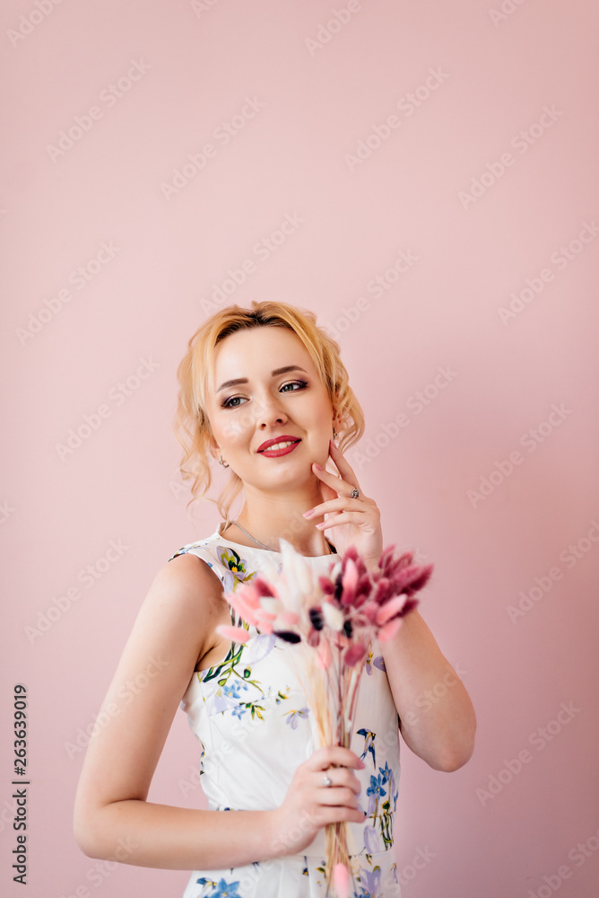 Beautiful young girl with blond hair is standing with a bouquet of color on a pink background in a dress. Fashion Beautiful young girl with blond hair is standing with a bouquet of color on a pink background in a dress. Fashion