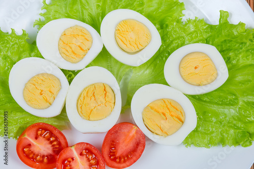 Halves of boiled chicken eggs and cherry tomatoes on lettuce