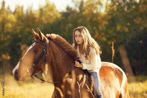 Young girl goes sorrel horse riding in field © Olga