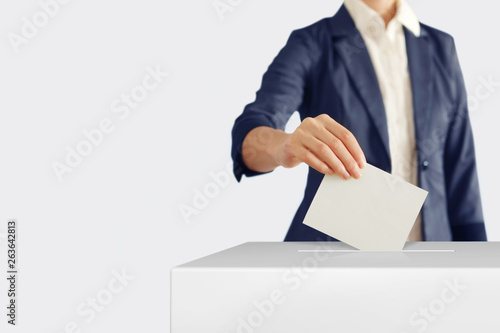 Voting. Woman putting a ballot into a voting box.
