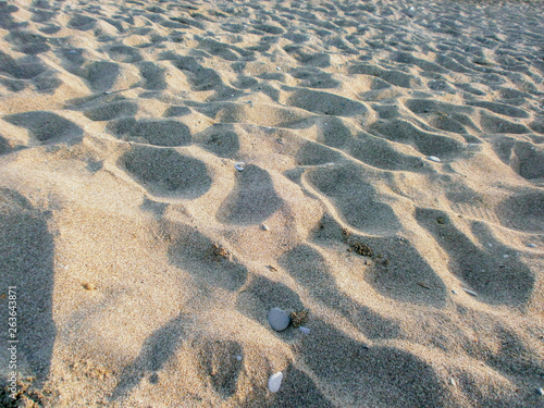 Background of beach sand with small pebbles. Indentations on the sand  craters .