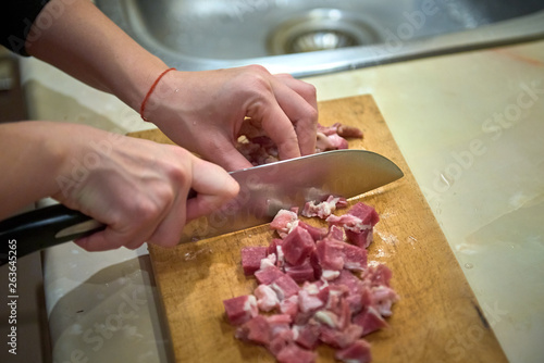 cutting meat on a kitchen board with a knife
