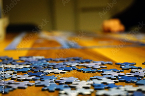 Making puzzle at home on wooden background bokeh effect close up view
