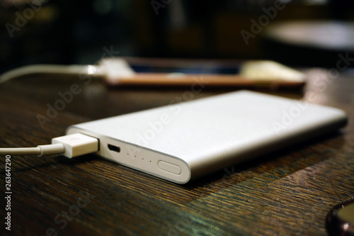 Powerbank charging smartphone on wooden background close up view