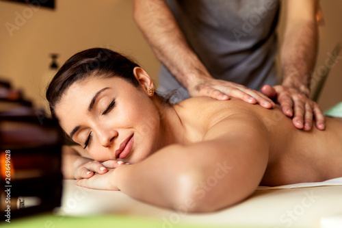 Beautiful young woman relaxing during full body massage at spa.
