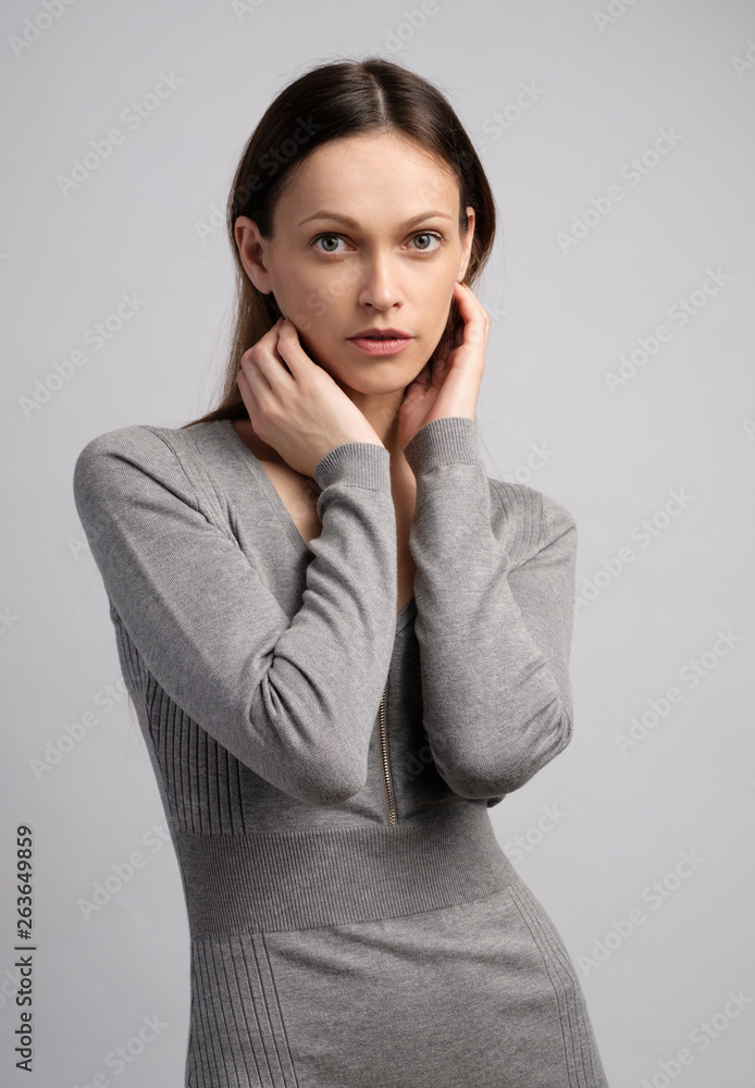 Cute young woman without any makeup in casual grey dress Cute young woman without any makeup in casual grey dress