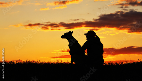 Silhouettes of girl and dog at sunset, breed Belgian shepherd Malinois, incredibly beautiful sunset, best friends together