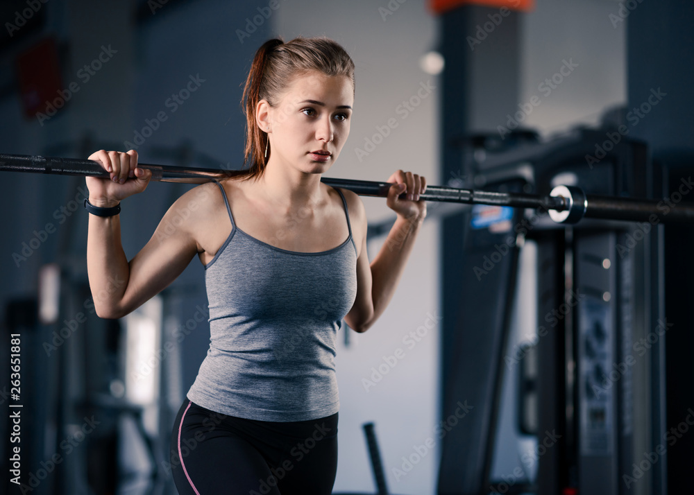 Fototapeta premium Attractive Young Sports Woman Doing Lunges with Barbell in the Gym. Fitness and Healthy Lifestyle.