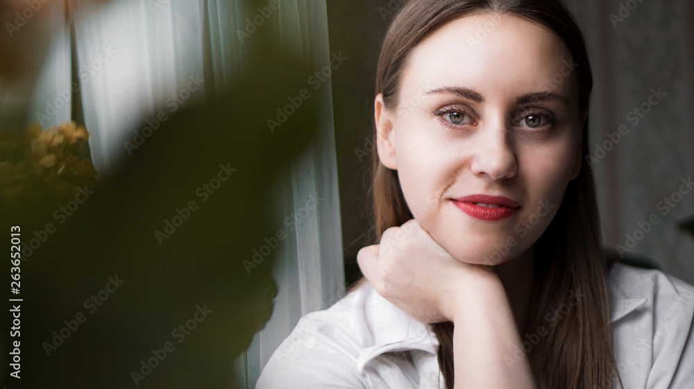 Portrait of attractive brunette woman. Home portrait of a woman with red lips in a white shirt