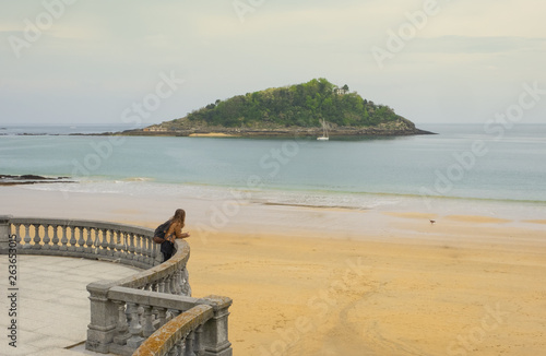 Traveling girl with backpack on the beach of La Concha, city of San Sebastian