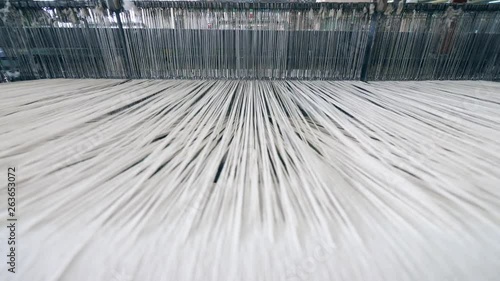 A loom weaving threads, working automatically at a factory. photo