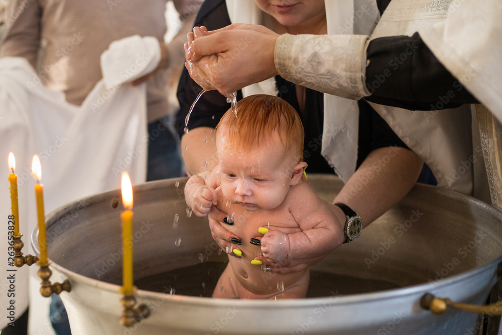Newborn baby baptism in Holy water. baby holding mother's hands. Infant