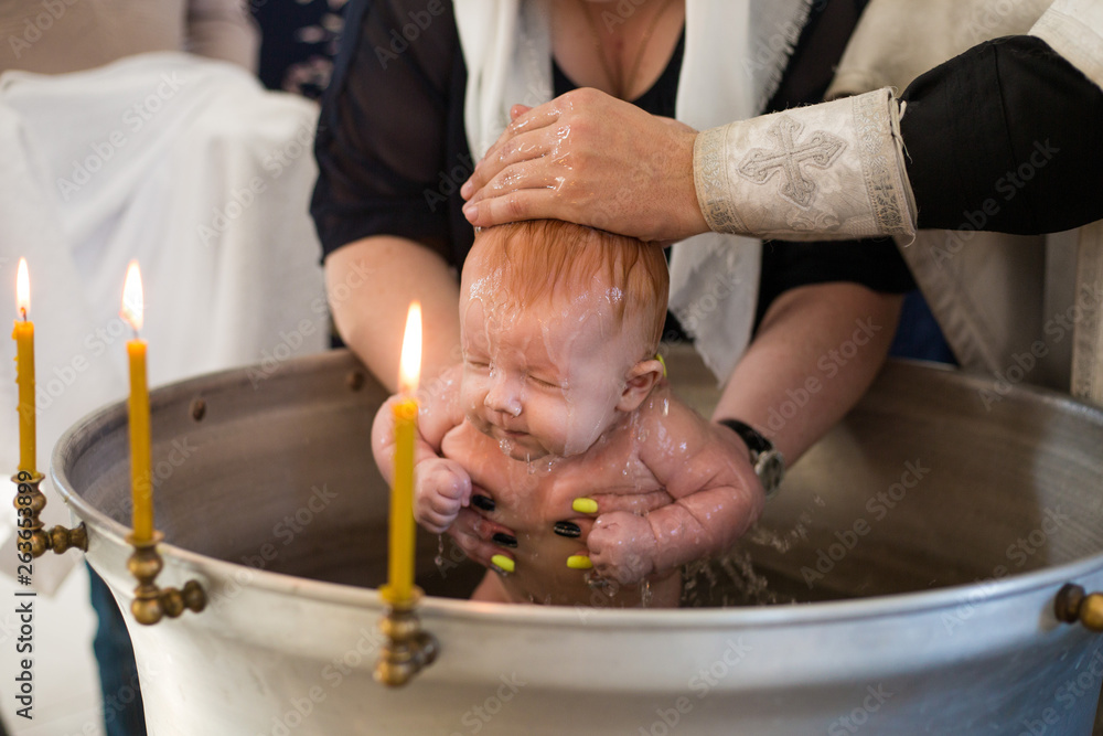 Newborn baby baptism in Holy water. baby holding mother's hands. Infant