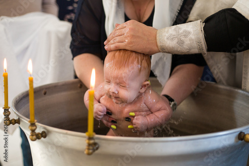 Fototapeta Newborn baby baptism in Holy water