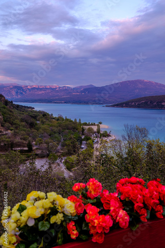 Obraz na płótnie Vue panoramique sur le lac de Sainte-Croix au printemps. Coucher de soleil. Provence. France. Photo verticale. Fleurs rouges et jaunes au premier plan. w salonie
