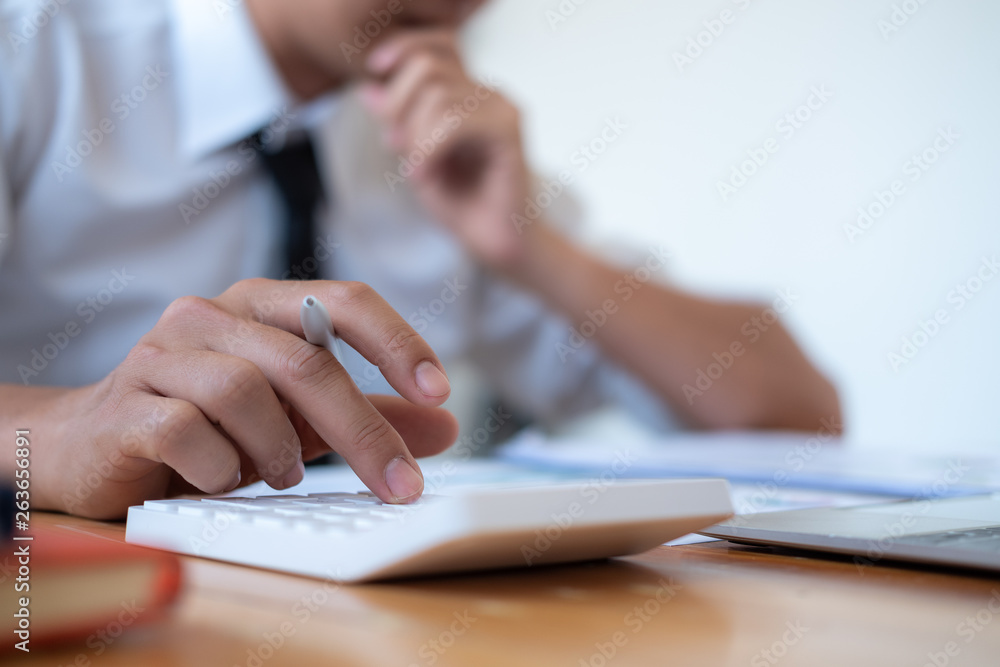 Businessman making calculation with pen in hand, finances concept Businessman making calculation with pen in hand, finances concept