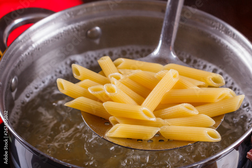 young woman in a gray apron is preparing pasta pesto