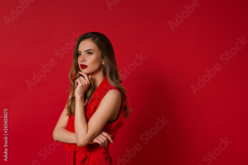 Portrait of young beautiful elegant woman smiling looking away over red background.