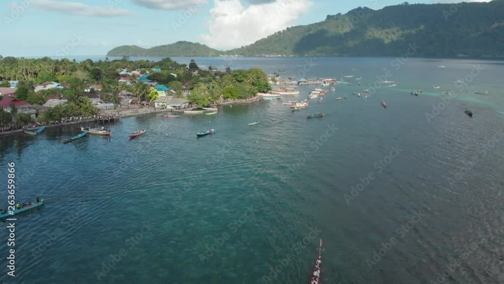 Aerial: kora-kora traditional canoe annual race in Bandaneira and speed boats sailing in the beautiful sea of the Banda Islands, Maluku, Indonesia. Native cinelike D-log color profile Aerial: kora-kora traditional canoe annual race in Bandaneira and speed boats sailing in the beautiful sea of the Banda Islands, Maluku, Indonesia. Native cinelike D-log color profile