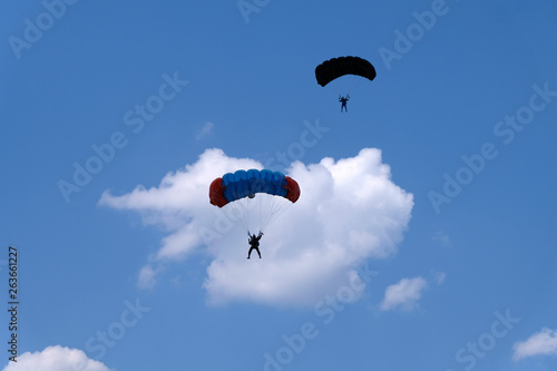 Two parachutists are in the sky.