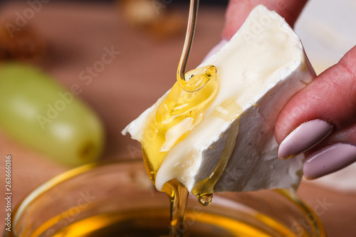 a young woman in a gray apron pouring honey Camembert cheese